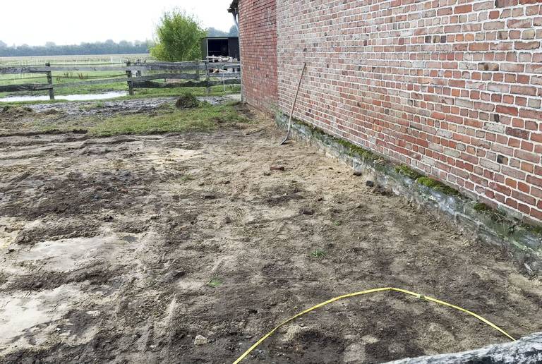 Erdige Bodenfläche an Backsteinhauswand