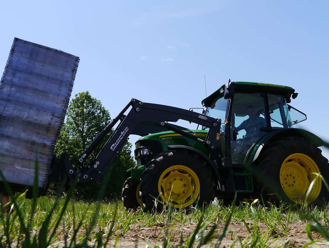 Seitliche Ansicht eines Traktors, der einen Stapel ECORASTER aufhebt