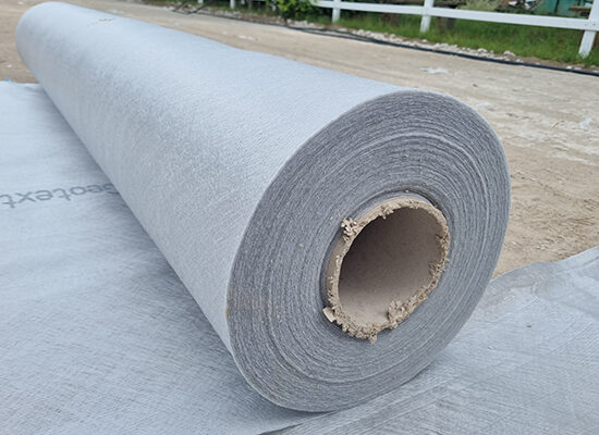 Nahaufnahme einer grauen Rolle von Geotextil auf einem Reitplatz